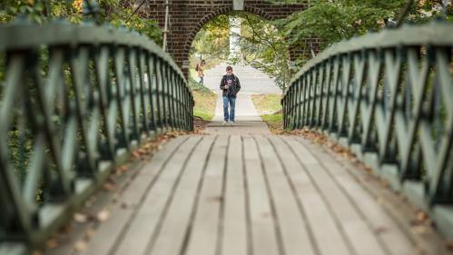 A student walks across the kissing bridge