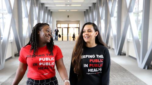 two smiling students wear shirts that say keeping the public in public health