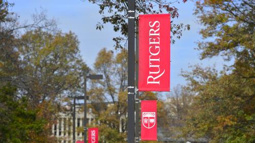 Red Rutgers flags line a sidewalk on Busch Campus