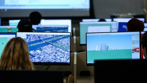 Students in a classroom setting looking at city maps on computers