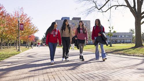 Four students wearing Rutgers shirts walk on Livingston Campus.