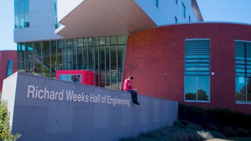 Student sitting outside of the Richard Weeks School of Engineering building