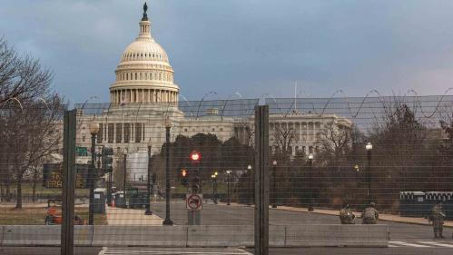 A view of the United States Capitol can be seen from behind a fence.