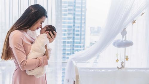 Women holds baby by a window.