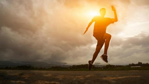 person jogging along a horizon with the sun behind