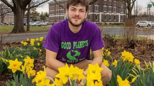 Rutgers senior Josh Kover crouches in a patch of daffodils outside Blake Hall in New Brunswick, N.J.