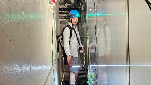 Man wearing constuction helmet standing in corridor between two metal walls