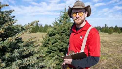Rutgers scientist Timothy Waller stands in a field of Christmas trees.