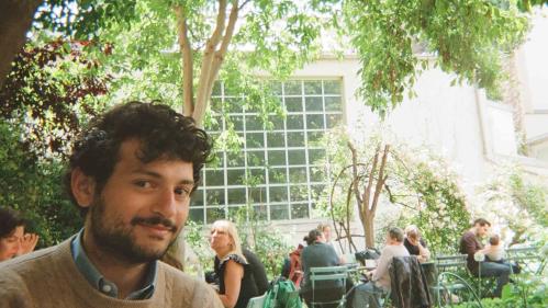 Tobias Robert Philip, who began his studies at Rutgers University-New Brunswick in 2020, sits outdoors in a shaded, patio area.