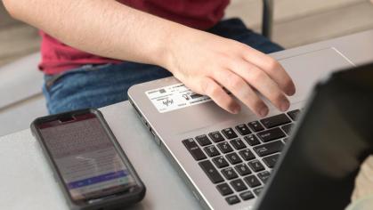 hand rests on open laptop