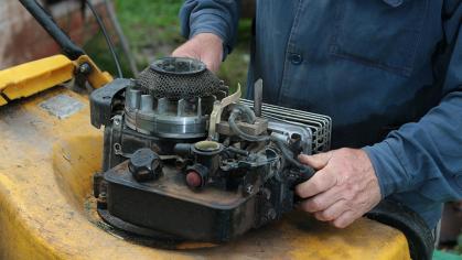 A man fixes a lawnmower engine
