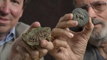 Researchers hold up roman coins