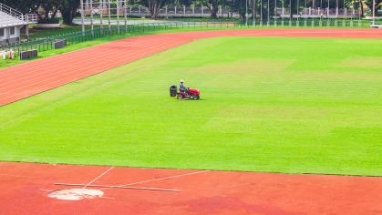 A person mows an athletic field