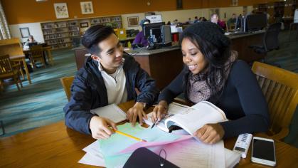 Two students sit and study together at a table in Alexander Library 