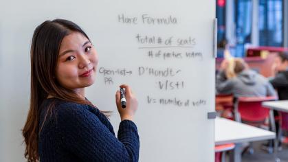 student writes the Hare formula on a board