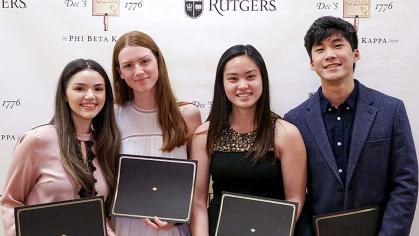 four students hold certificates dring Phi Beta Kappa induction ceremony