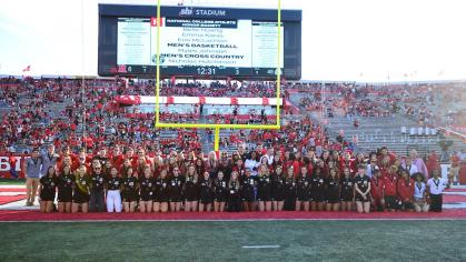 Student athletes pose as a group on a field
