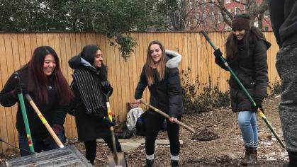 Students dig in a yard during a community service project 