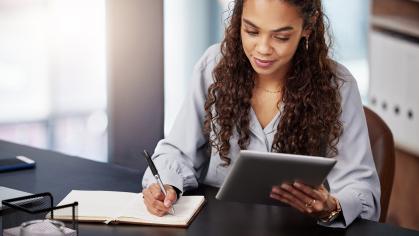 person holding a tablet and writing notes