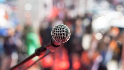 A microphone in front of a blurred group of people.