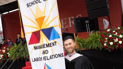 An SMLR graduate holds a banner at commencement