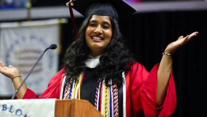 Nina Gohel speaking at a podium during the graduation ceremony