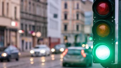 A traffic signal in a city with the green light illuminated