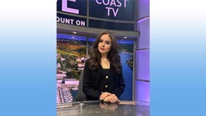 Eleisa Weber JMS’23 sitting at the anchor desk of WRDE CoastTV News