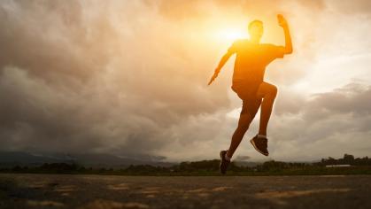 person jogging along a horizon with the sun behind
