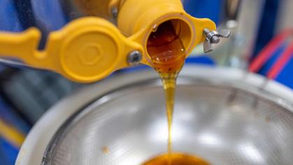 Honey dripping from a machine into a sieve for filtering.