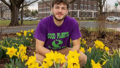 Rutgers senior Josh Kover crouches in a patch of daffodils outside Blake Hall in New Brunswick, N.J.