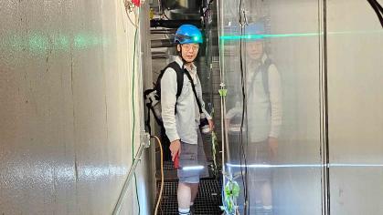 Man wearing constuction helmet standing in corridor between two metal walls