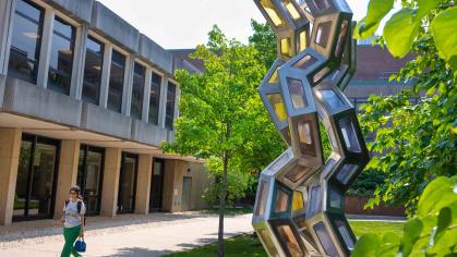 A student walks by the sculpture “Synergy” outside of the Proteomics Building on Busch campus at Rutgers-New Brunswick.