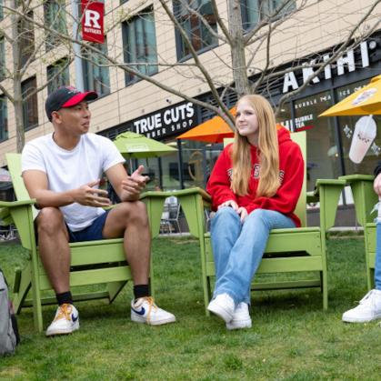 students seated in adirondack chairs chatting at The Yard