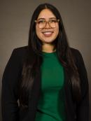 Melanie Ingles in a black blazer and green top and wearing glasses