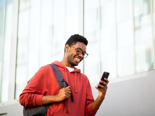 A student wearing a red sweatshirt looks at his phone.