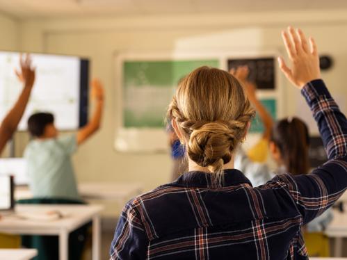 In high school, students raising hands in classroom, actively participating in lesson