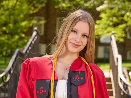 Anna Vernikov in front of the Old Queens gate holding her graduation cap.