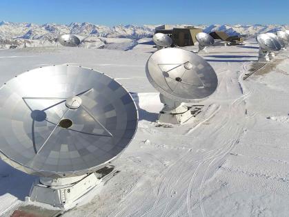 An array of telescopes on a snow-capped mountain.