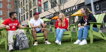 four students sitting in adirondack chairs at the Yard