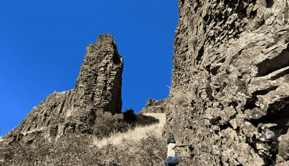 A tower of rock on the left and the face of a mountain in foreground.