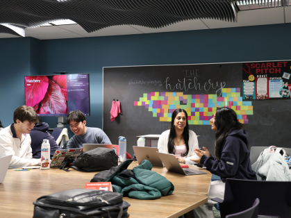 Students gathered around a table collaborating and laughing
