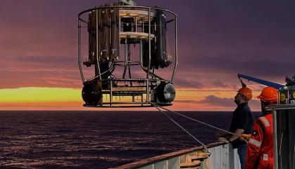 Workers on a ship raising a research instrument before lowering it in the ocean