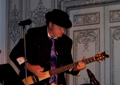 Singer-songwriter Mike Kovacs plays a guitar during a performance.