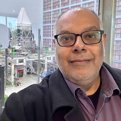 Saurabh Jha poses in front of the Nancy Grace Roman Telescope, a NASA infrared space telescope set to launch into orbit by May 2027.