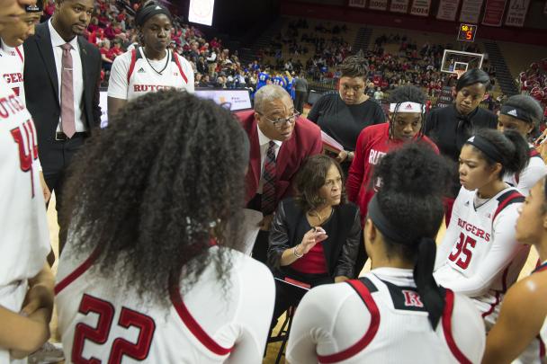 The women's basketball head coach goes over plays with her team during a game