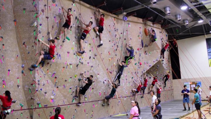 Students climb the rockwall at the college avenue gym