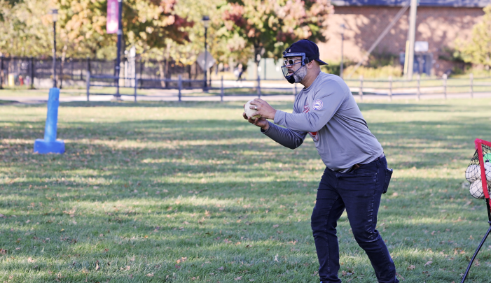A student wearing an eye cover takes a pitch while playing beep baseball, an adaptive sport for blind athletes