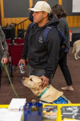 A student pets a service dog at an event for Disability Awareness Month