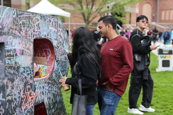 Attendees write with chalk on a big block R sculpture on Rutgers Day